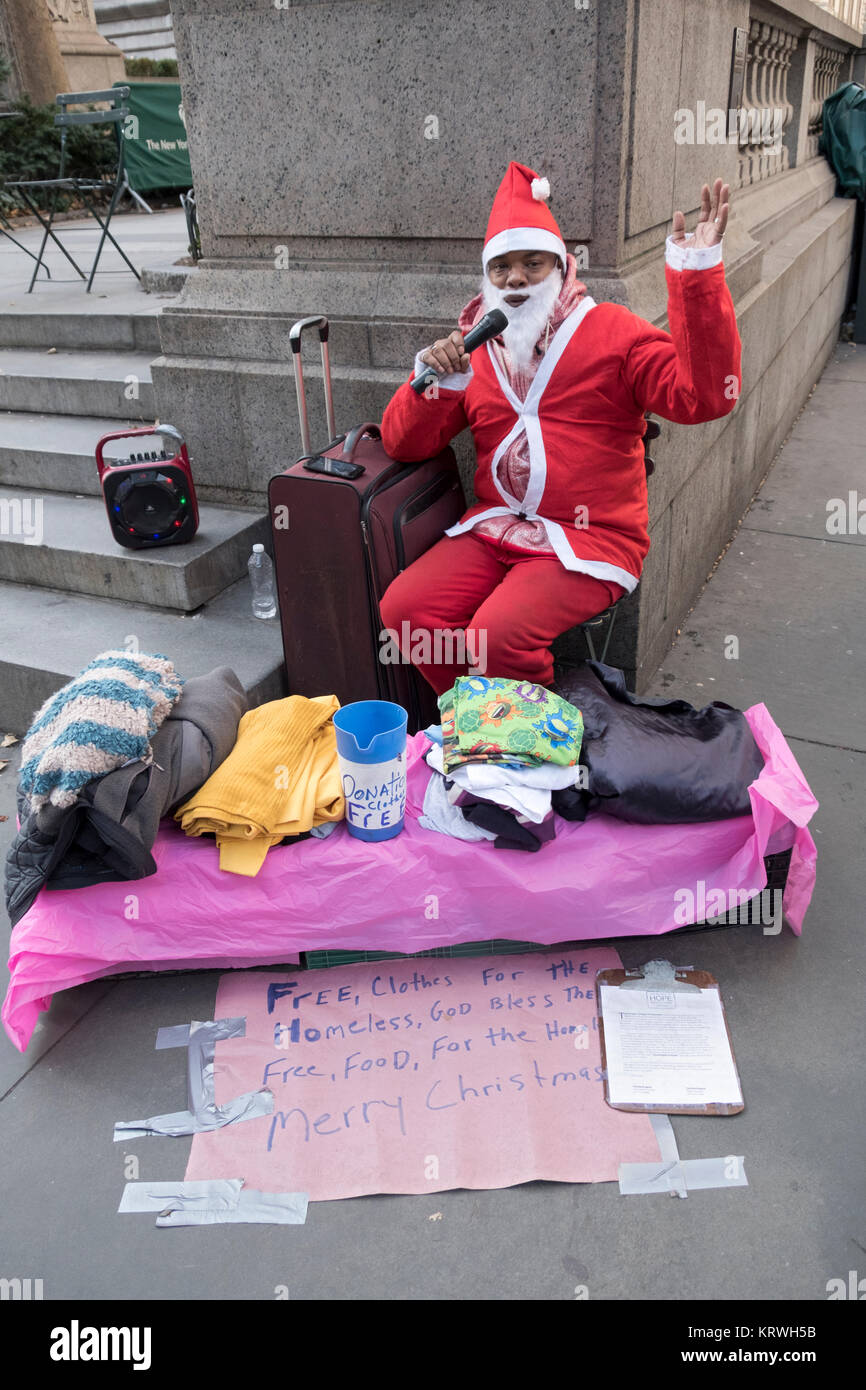 An advocate for the homeless dressed as Santa distributing clothing and soliciting donations on Fifth Avenue & 42nd Street in Midtown Manhattan, NYC. Stock Photo
