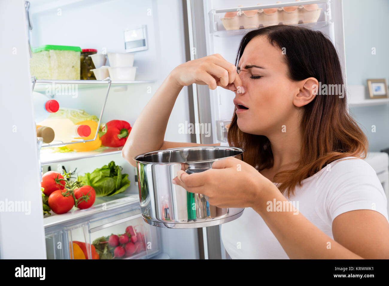 Woman Holding Foul Food Near Refrigerator Stock Photo
