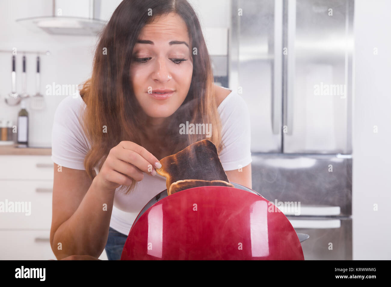 Woman Taking Burnt Toast Out Of The Toaster Stock Photo Alamy