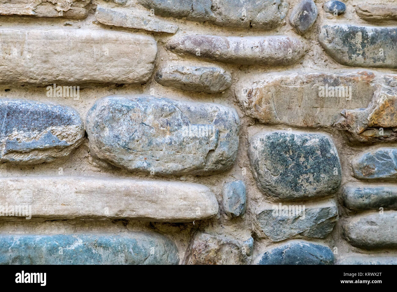 Fragment of the ancient stone wall executed from stones of various form and the size. Background image. Stock Photo