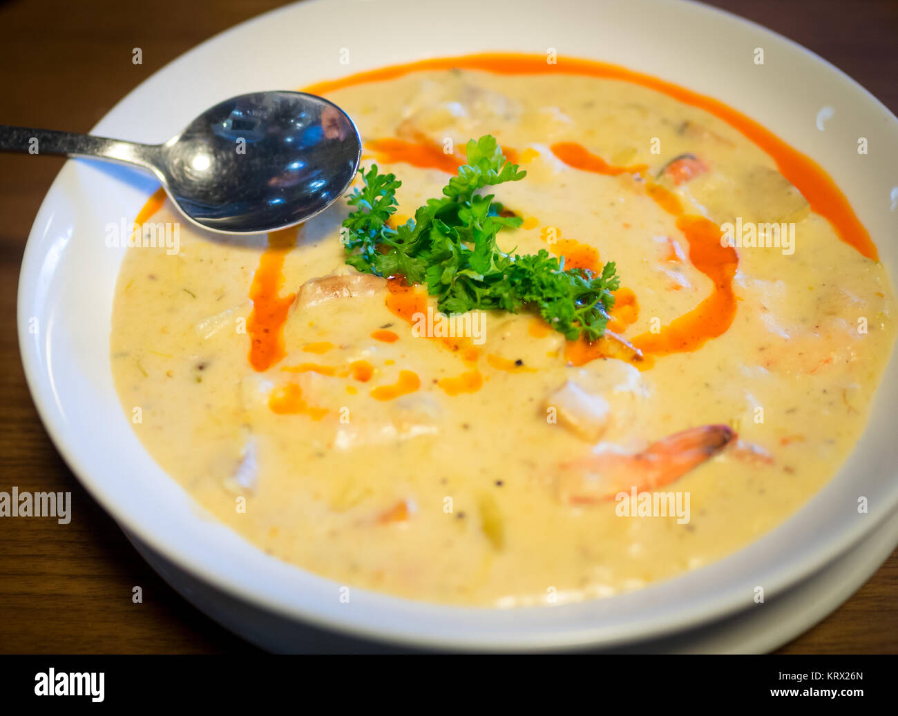 A bowl of seafood chowder with scallops, shrimp, clams, and harissa oil