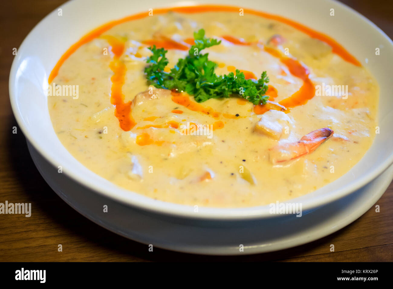 A bowl of seafood chowder with scallops, shrimp, clams, and harissa oil