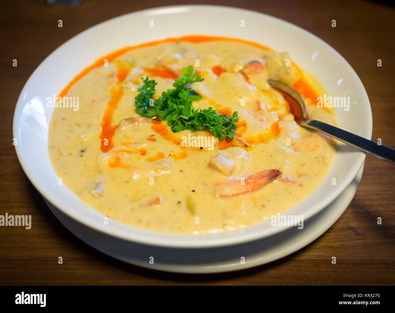 A bowl of seafood chowder with scallops, shrimp, clams, and harissa oil