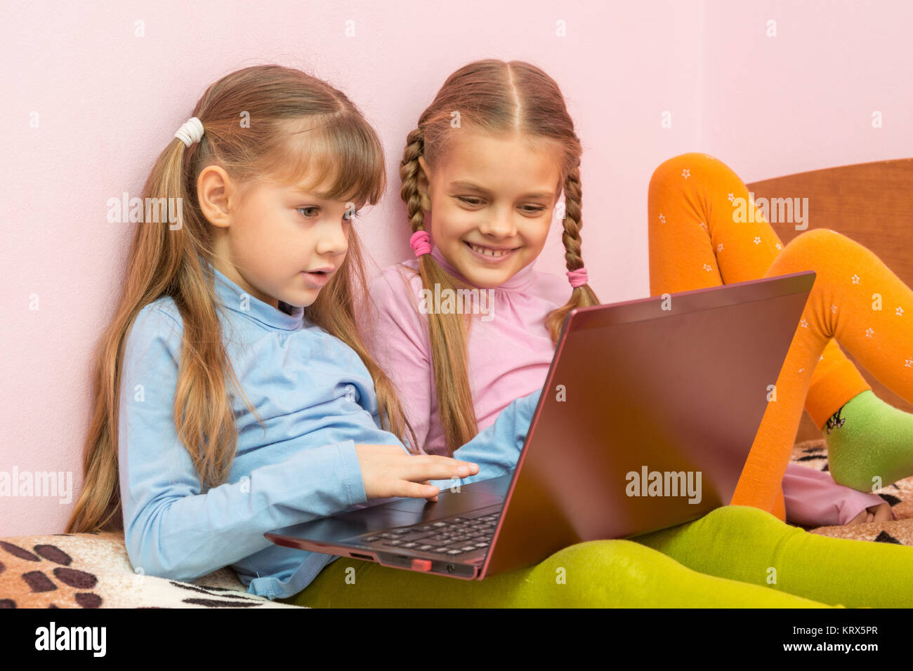 Two girls play computer games on a laptop Stock Photo