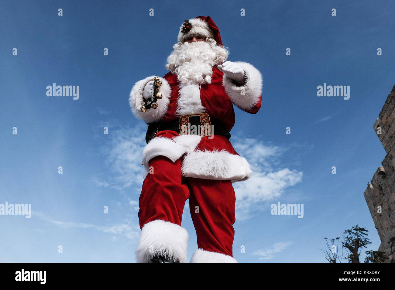 Jerusalem, Israel. 21st December, 2017. Santa Claus, or 'Baba Noel' as he is called in Arabic, walks on the Old City walls overlooking Jerusalem. The Jerusalem Municipality and the Jewish National Fund distributed specially grown Arizona Cypress Christmas trees to the Christian population at the Jaffa Gate. Credit: Nir Alon/Alamy Live News Stock Photo