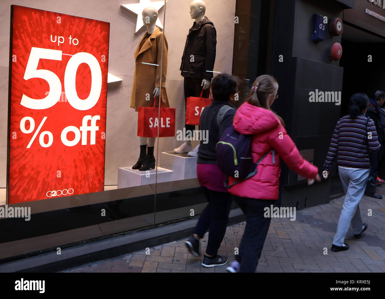 Hong Kong, China. 21st Dec, 2017. People walk past a sale post of a store in Hong Kong, south China, Dec. 21, 2017. Stores in Hong Kong offer discount to attract customers as Christmas and New Year draw near. Credit: Li Peng/Xinhua/Alamy Live News Stock Photo