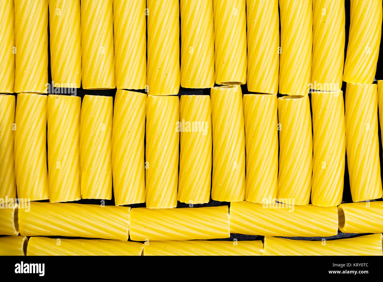 A variety of dry Italian pasta shapes scattered artistically on a wooden background.
