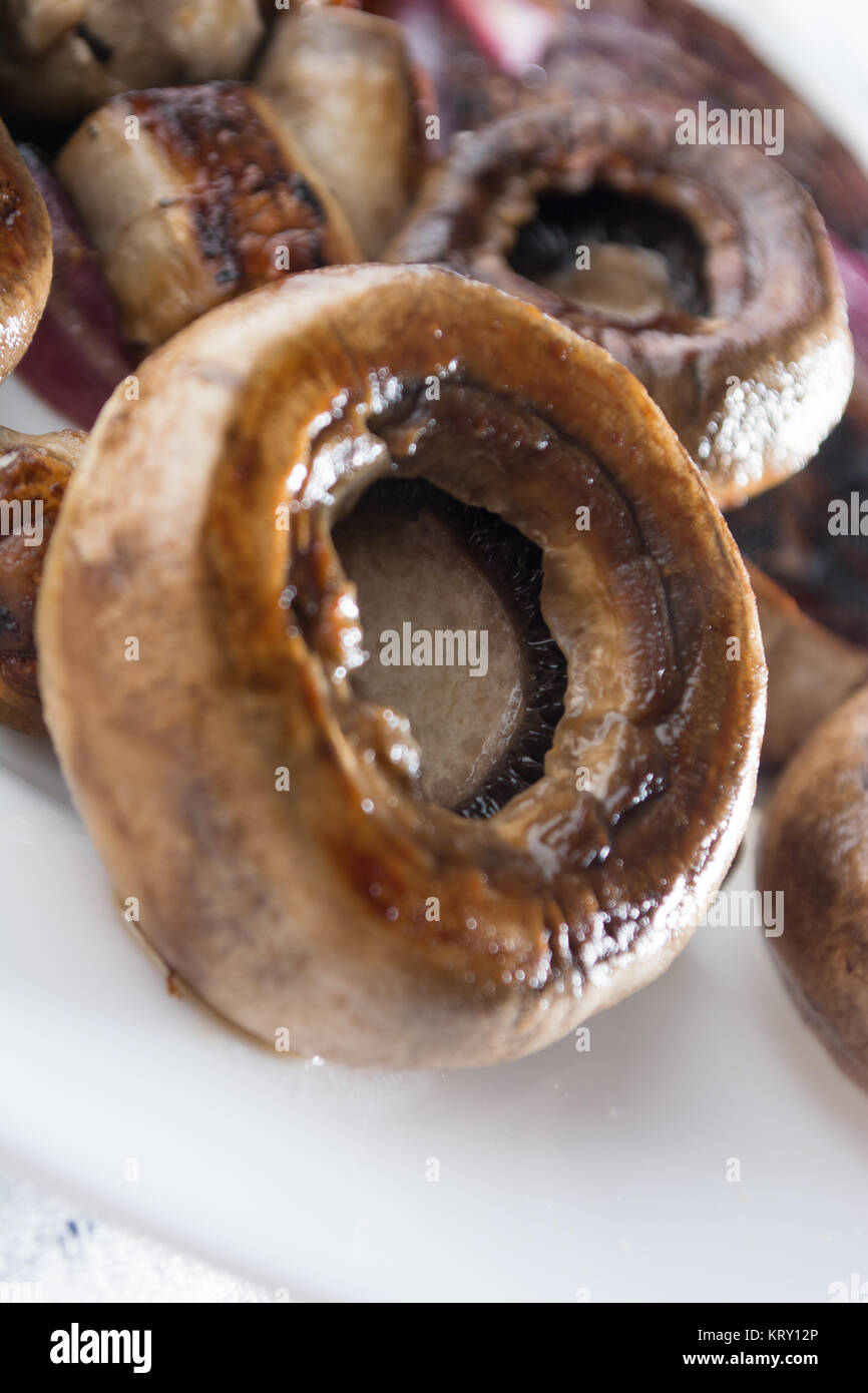 Close up of roasted juicy mushrooms with onion on white plate Stock Photo