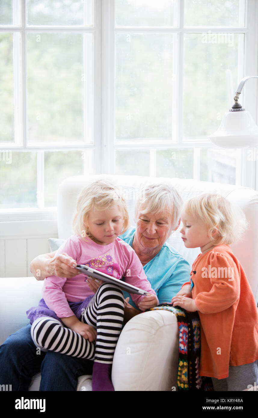 Grandmother and grandchildren looking at a tablet Stock Photo