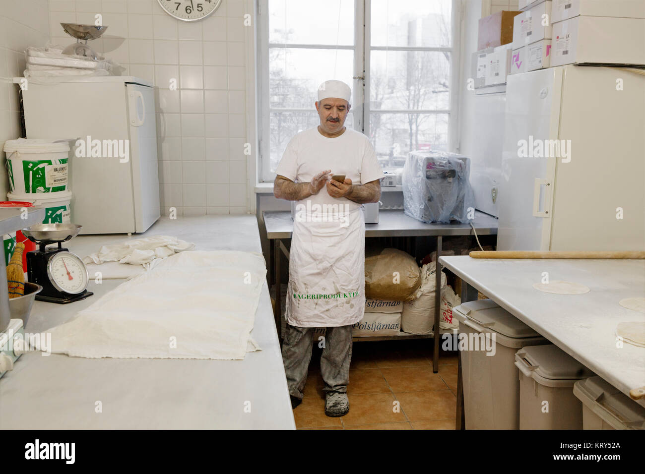 Chef holding smart phone in kitchen Stock Photo
