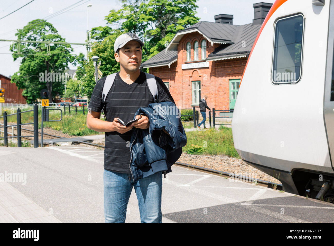 Man holding smart phone on train platform Stock Photo