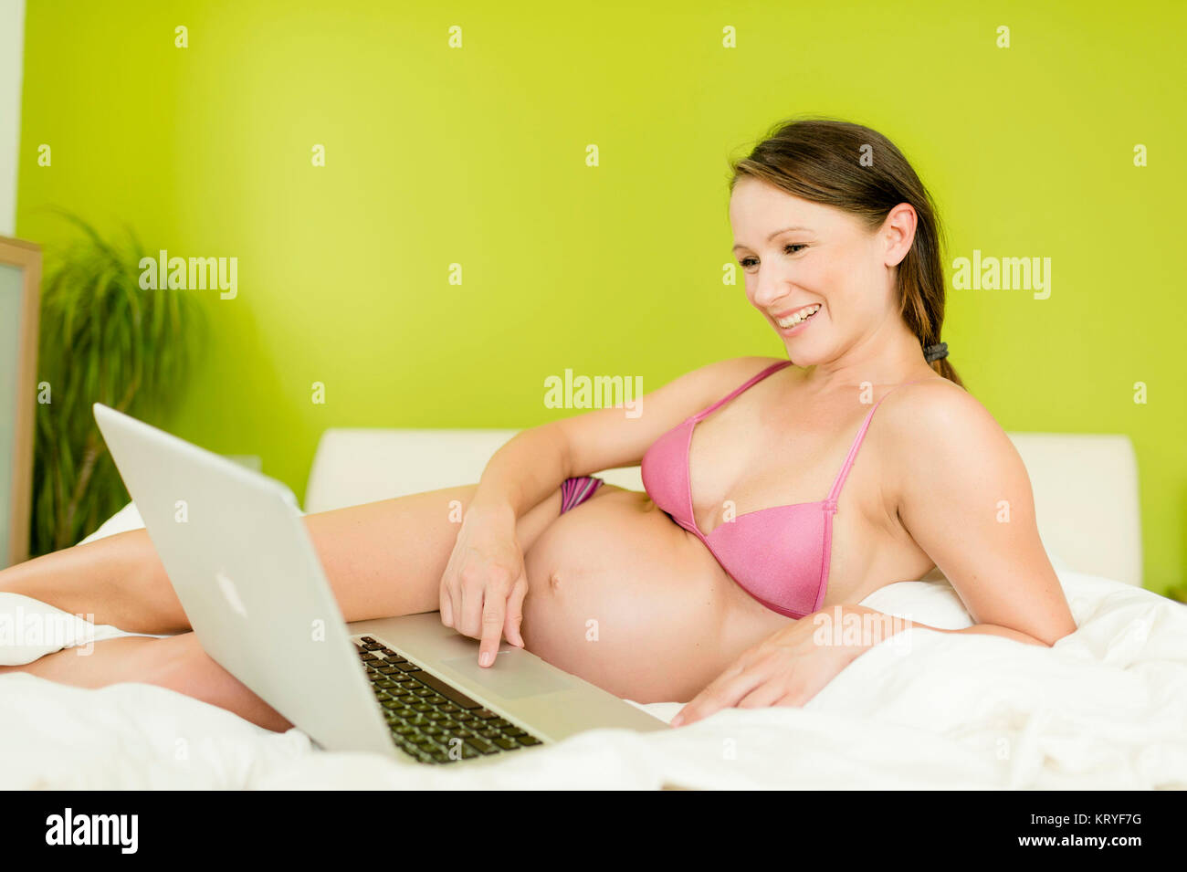 Schwangere Frau mit Laptop im Bett - pregnant woman with laptop Stock Photo