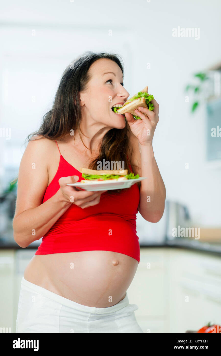 Schwangere Frau isst ein Sandwich - pregnant woman eats a sandwich Stock Photo