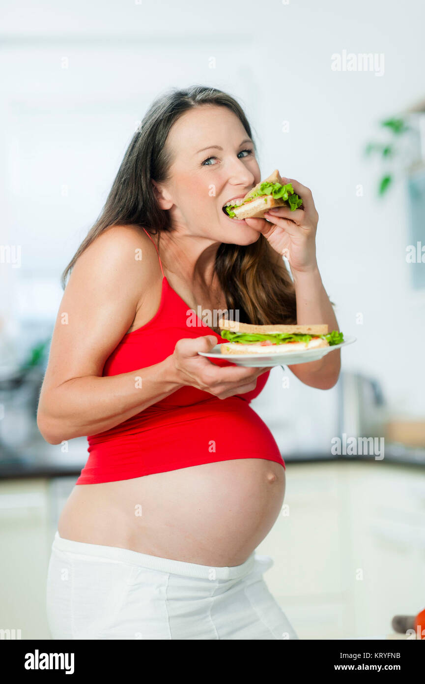 Schwangere Frau isst ein Sandwich - pregnant woman eats a sandwich Stock Photo