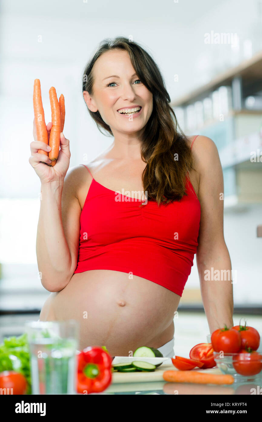 Schwangere Frau mit Gemüse beim Kochen in der Küche - pregnant woman with vegetables in kitchen Stock Photo