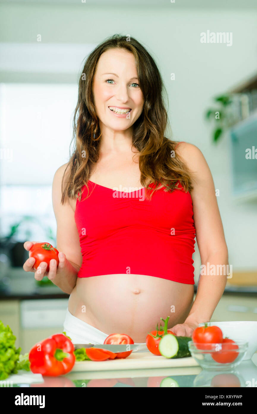Schwangere Frau mit Gemüse in der Küche - pregnant woman cooking with vegetables Stock Photo