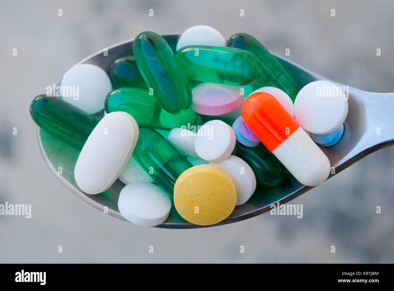 Spoon full with prescription drugs, gel capsules and vitamins Stock