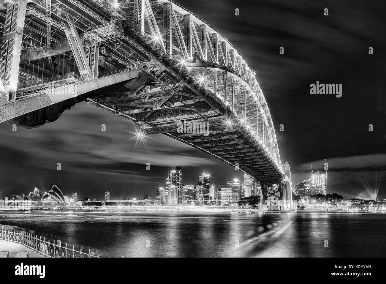Architectural landmarks of Sydney at dark during light show. Arch of Harbour Bridge above the head towards city CBD and Circular quay behind blurred w Stock Photo