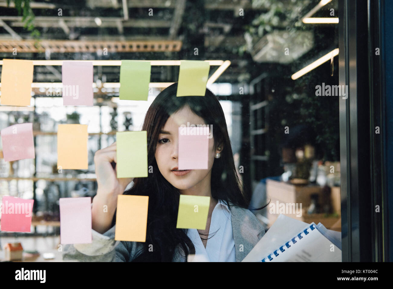 Businesswoman write on adhesive notes on glass wall in meeting room at ...