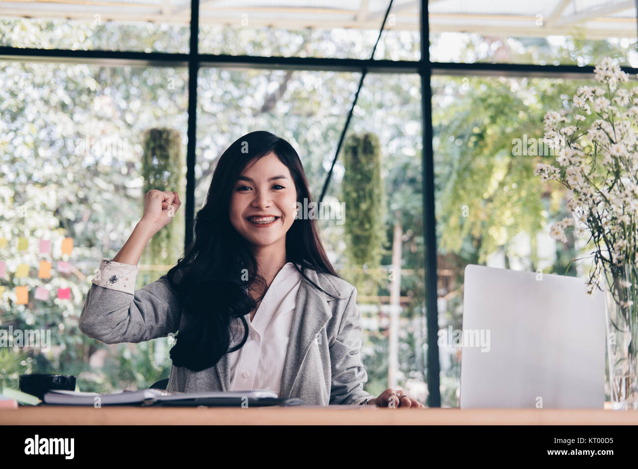 young start up woman raise fist with yes gesture at office. freelance female entrepreneur glad with successful project. businesswoman working at workp Stock Photo
