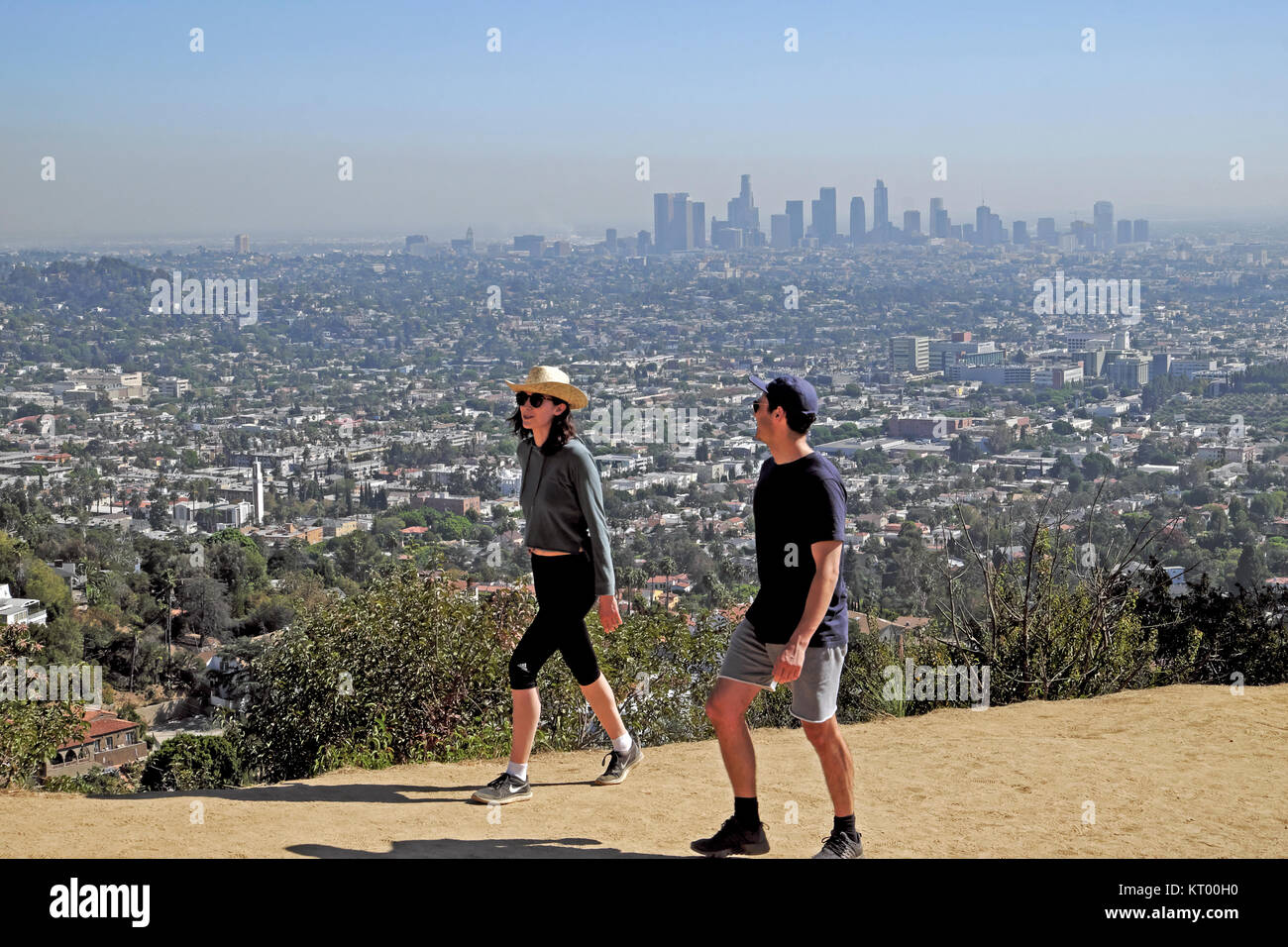 Two people hiking up trail path to Griffith Park Observatory in Griffith Park hills & cityscape of downtown Los Angeles, California USA   KATHY DEWITT Stock Photo