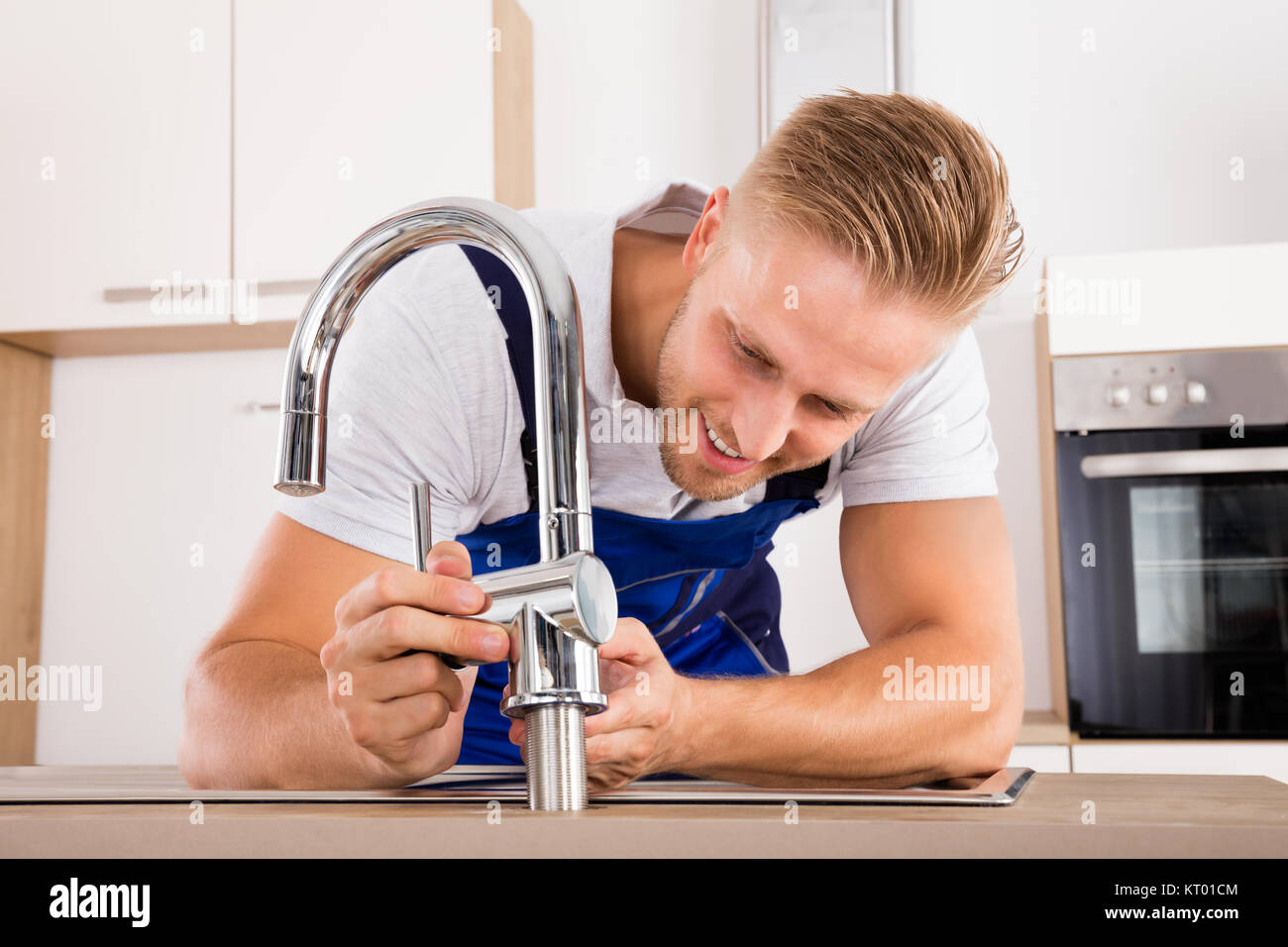 Plumber Fixing Faucet In Kitchen Stock Photo Alamy
