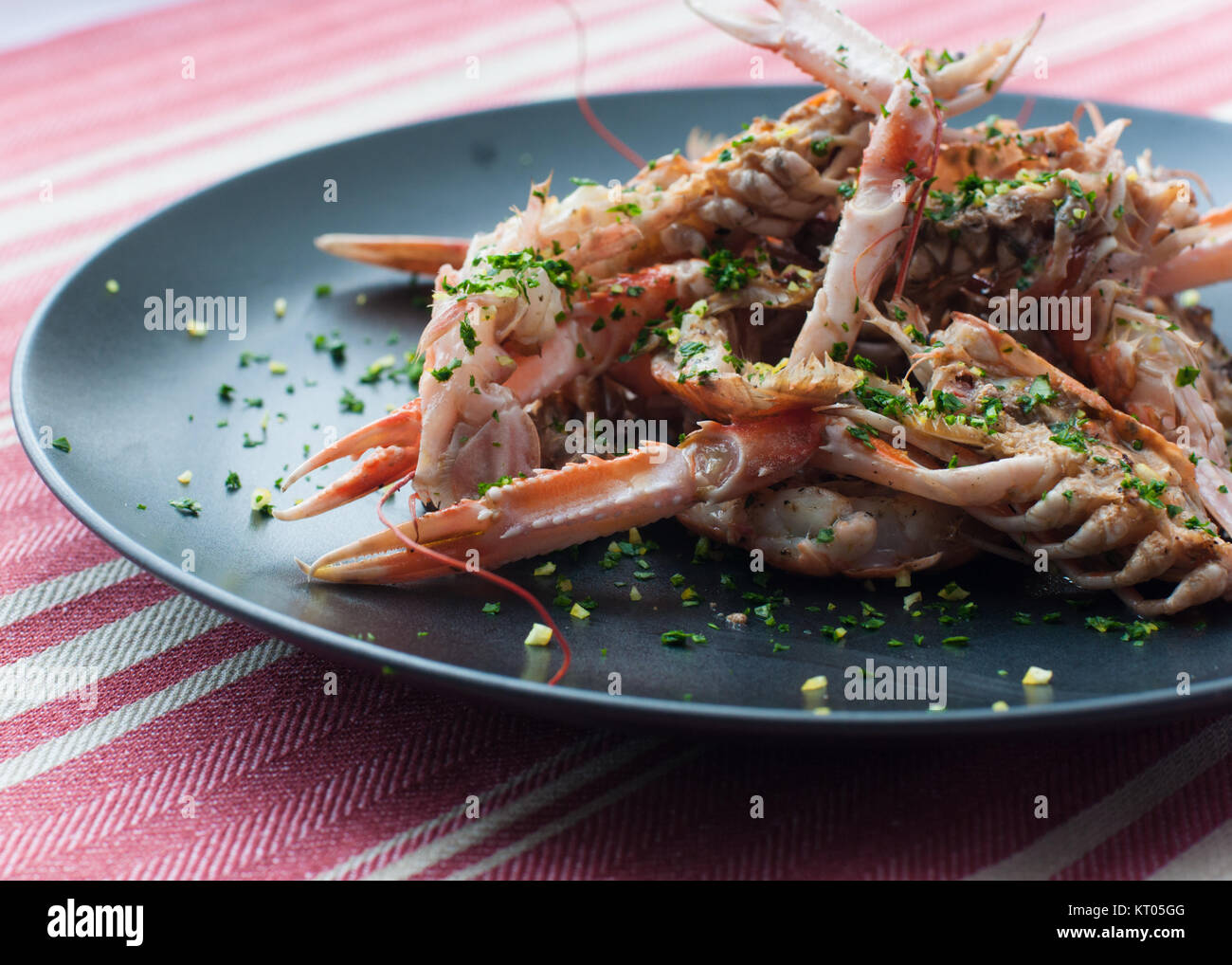 fresh cooked lobster with herbs on black plate with red and white stripe table cloth Stock Photo
