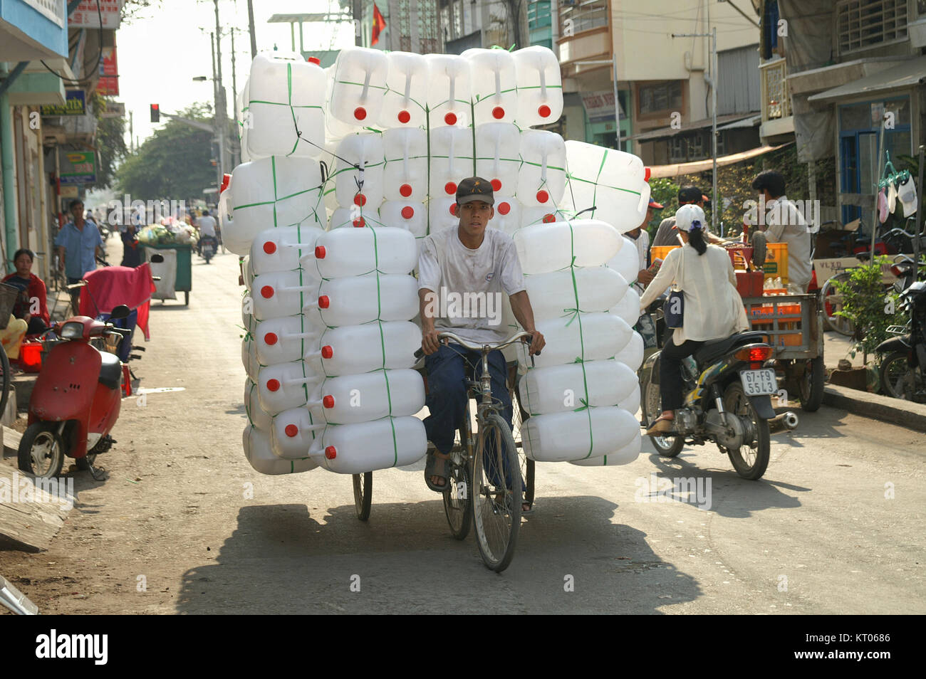 CHAU DOC, VIETNAM - JANUARY 30, 2005 : A man transporting a large number of empty plastic jerry cans strapped precariously to his three wheel bicycle. Stock Photo