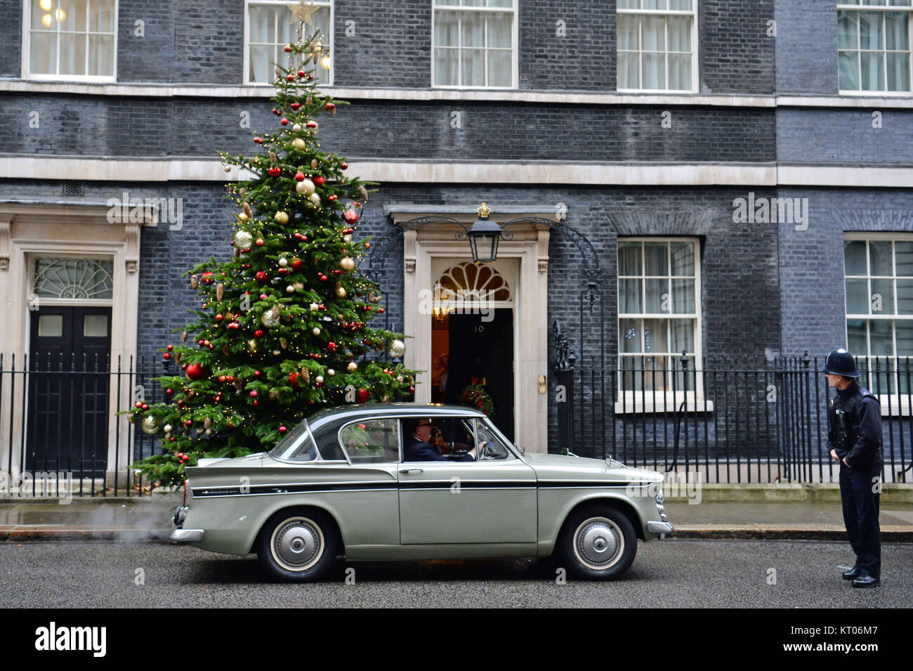 A police officer looks at Greg Knight MP arriving in Downing Street, London, in a 1961 Sunbeam Rapier car. Stock Photo