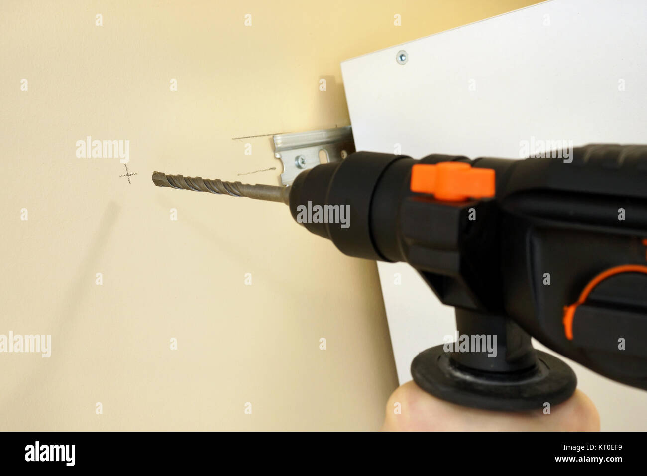 Drilling the wall with a perforator. Installation of a cabinet. Stock Photo