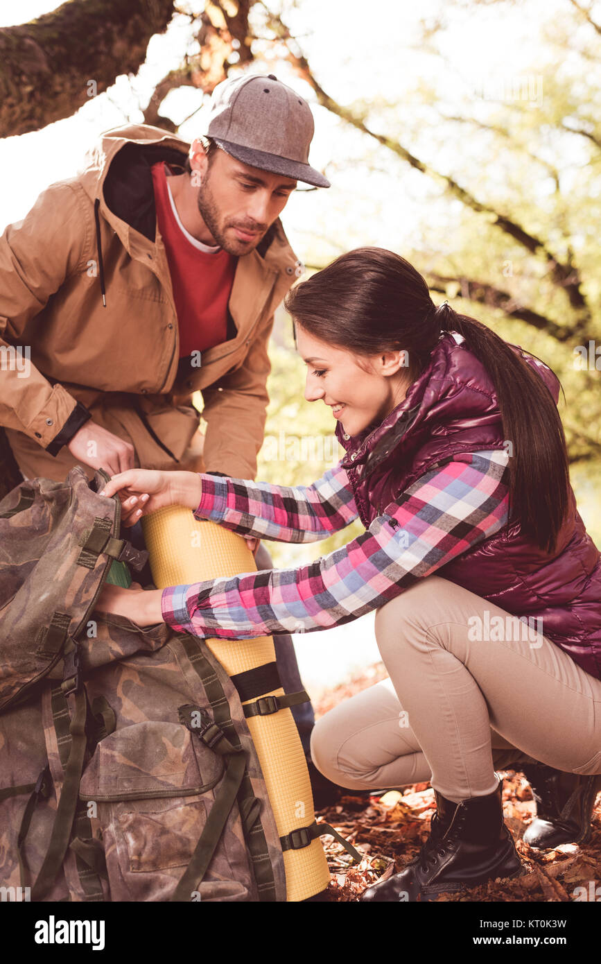 Man looking at woman packing backpack Stock Photo