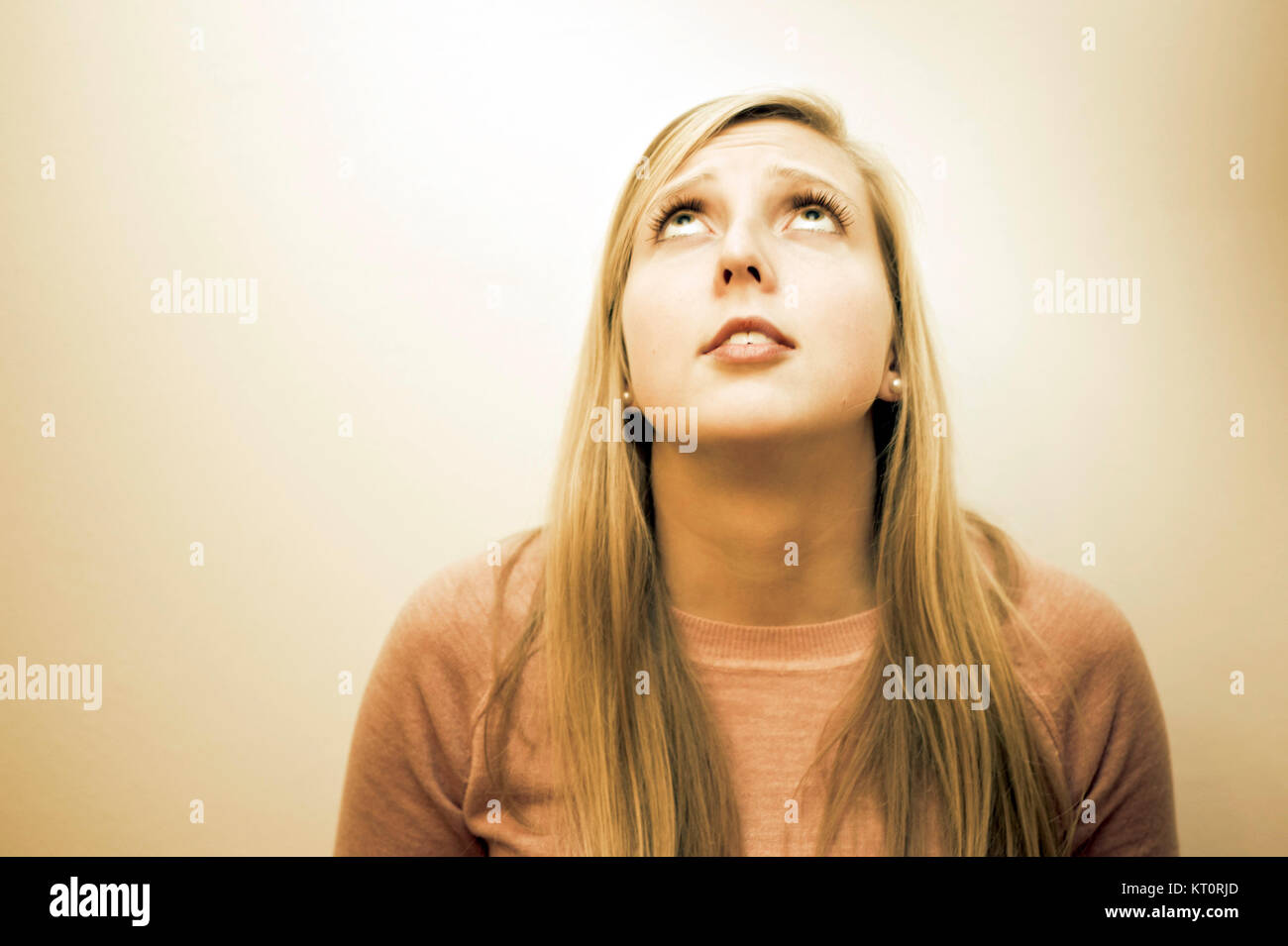 blonde young woman looking upward with a worried or wishful expression Stock Photo