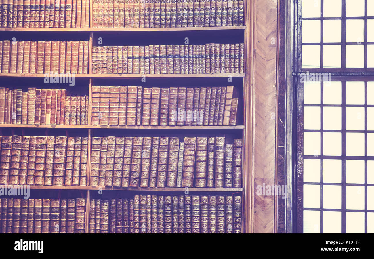 Vintage toned old books on wooden shelves, education concept background. Stock Photo