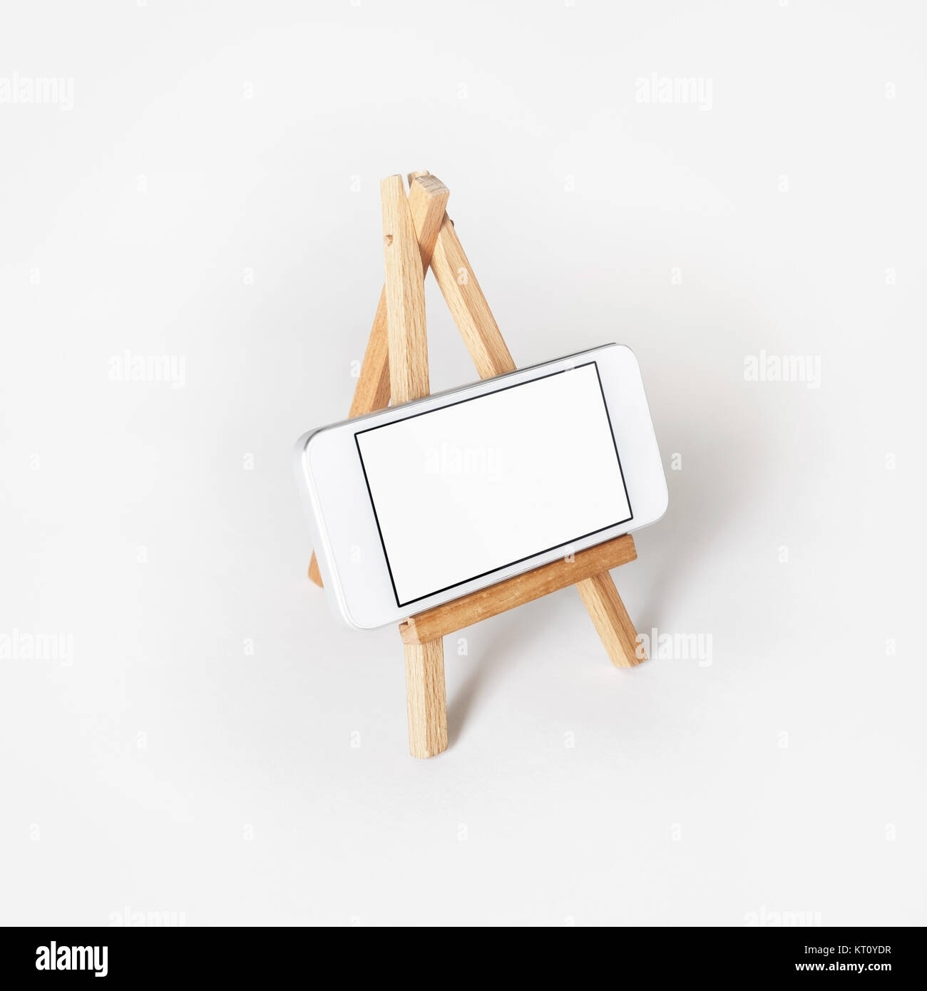 White smartphone on phone holder at white paper background. Stock Photo