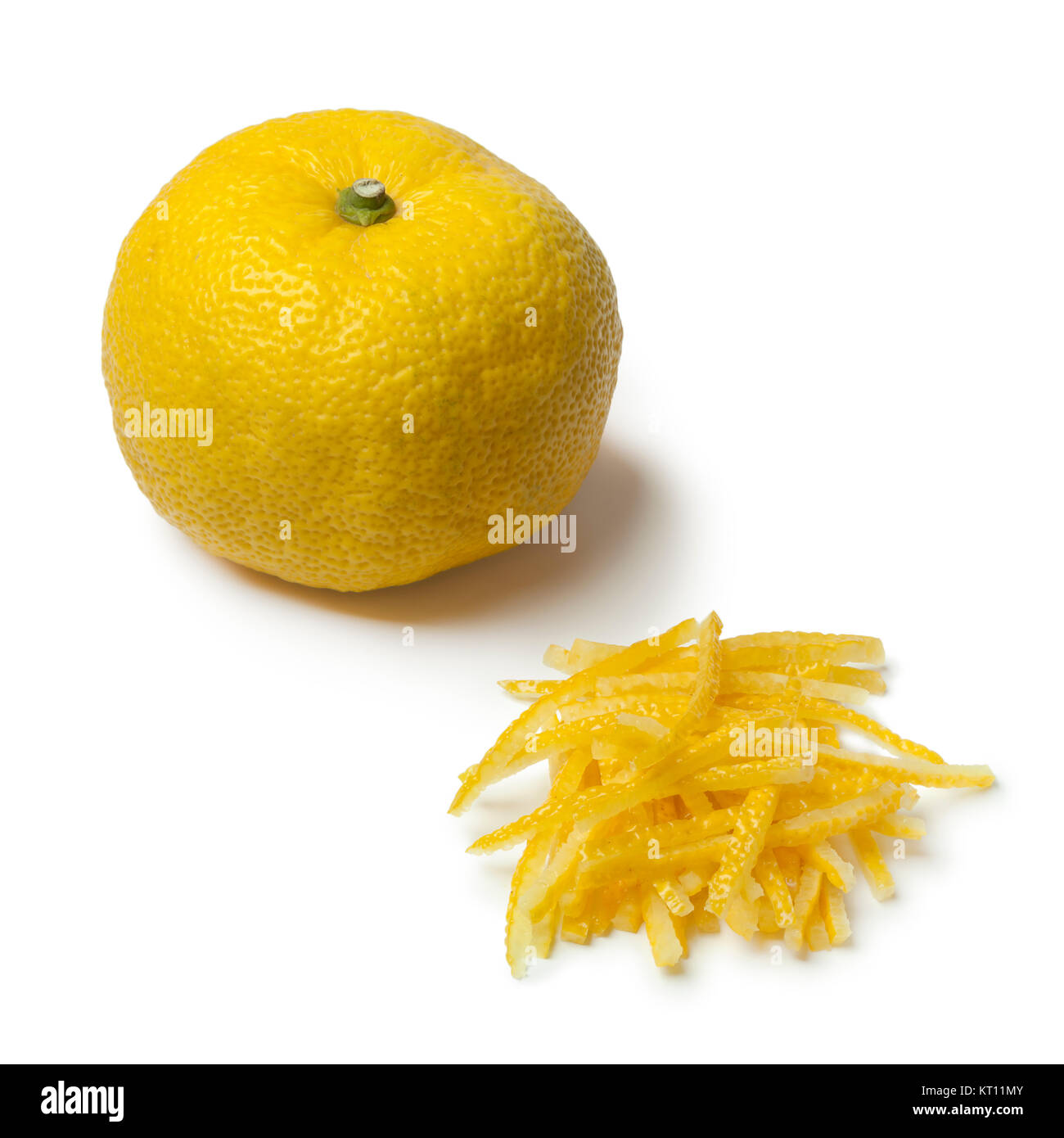 Fresh strips of a yellow Japanese Yuzu skin with a whole yuzu in the background  isolated Stock Photo