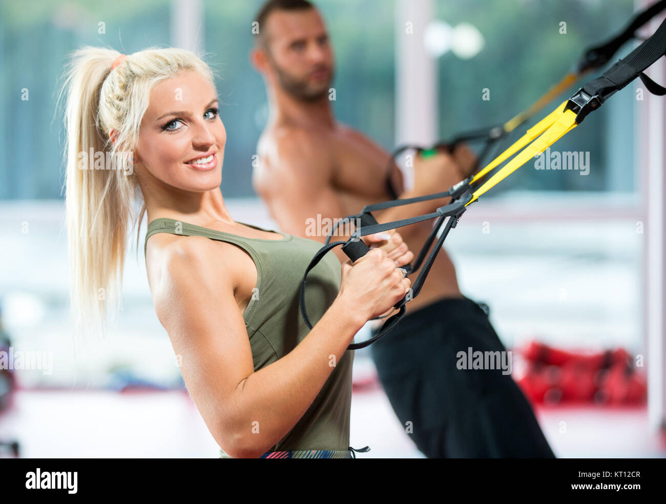 couple doing push ups training arms with trx fitness straps in the gym ...