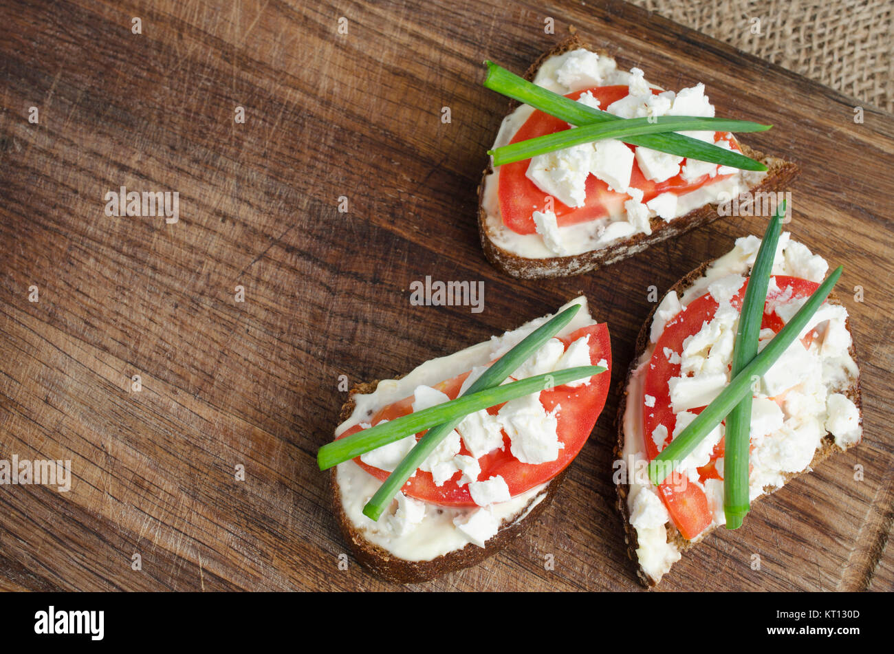 Slices of rye bread with sire feta and tomato. Stock Photo