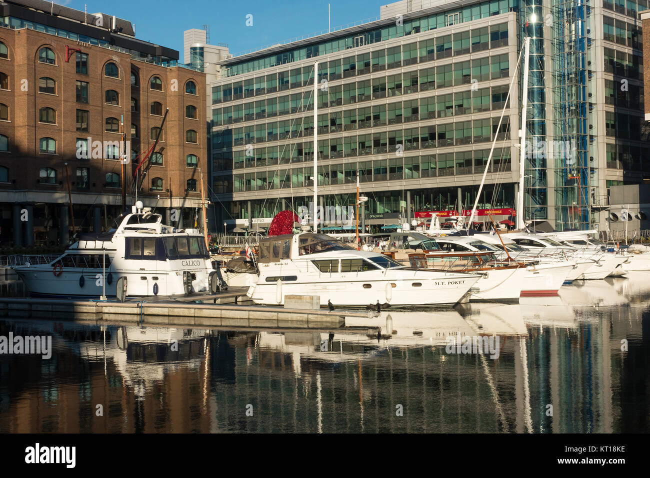 Luxury Boats Moored and Docked in the Safety of St Katharine Dock with Reflections on Water Tower Hamlets London England United Kingdom UK Stock Photo