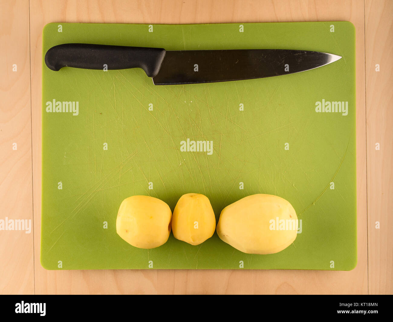 https://c8.alamy.com/comp/KT18MN/three-potatoes-and-knife-on-green-plastic-board-KT18MN.jpg