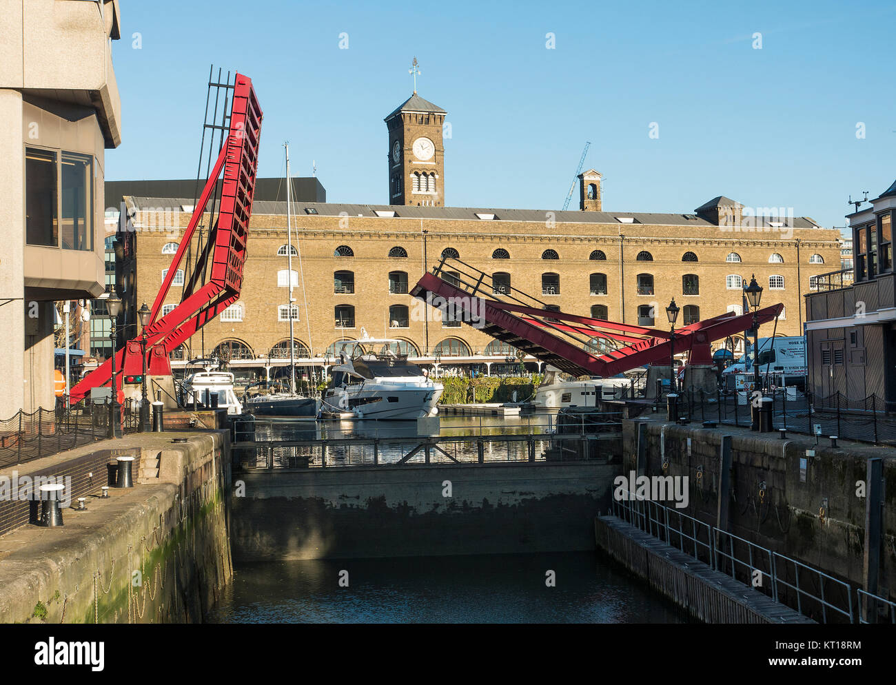 The Entrance from the River Thames into St Katharine Dock with Raised Red Access Bridge over Lock Tower Hamlets London England United Kingdom UK Stock Photo