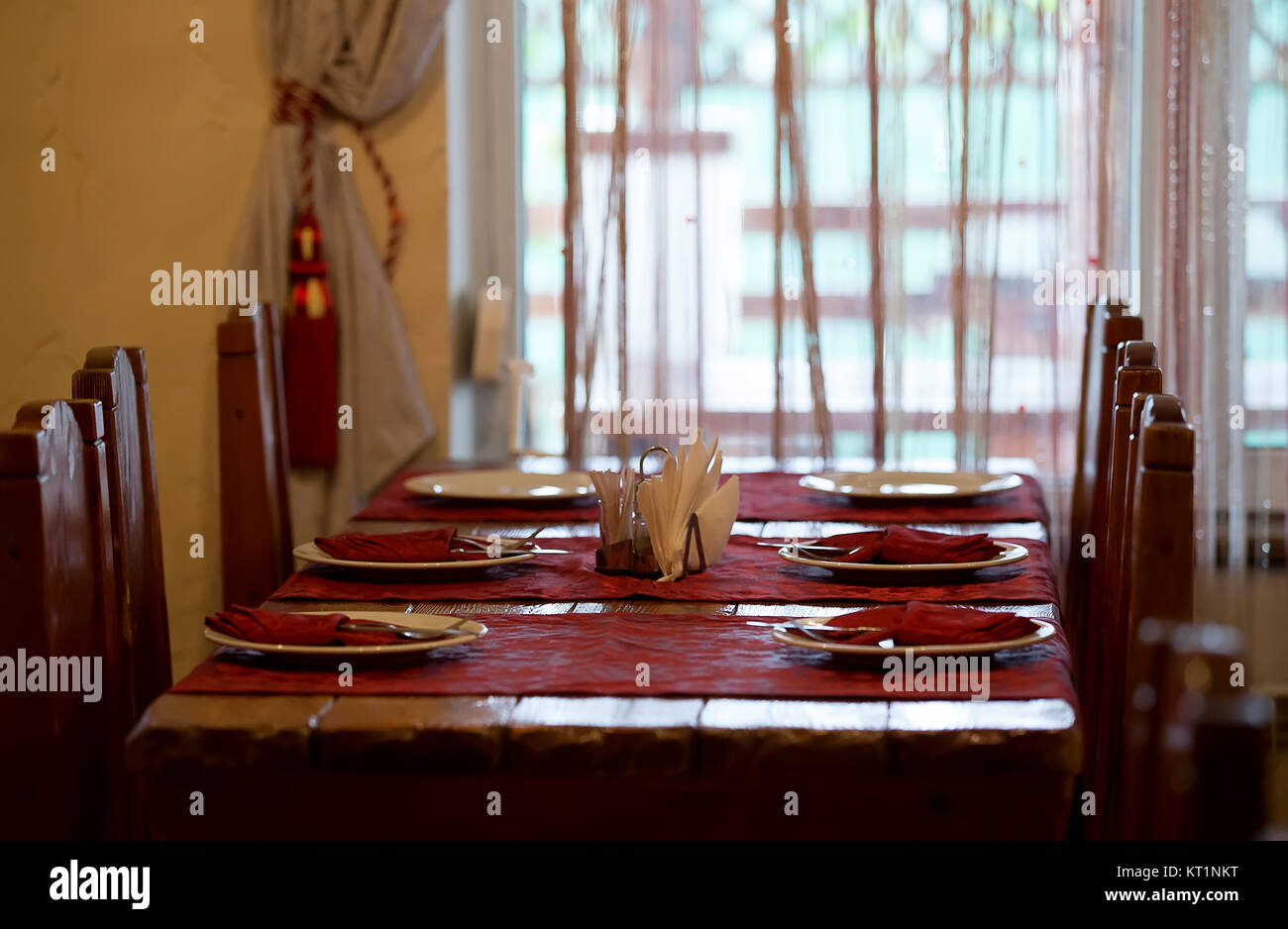 The restaurant .Empty restaurant. Table setting. Prepare for a banquet. Festive table.s a long table served, tablecloths and a bouquet of flowers on t Stock Photo