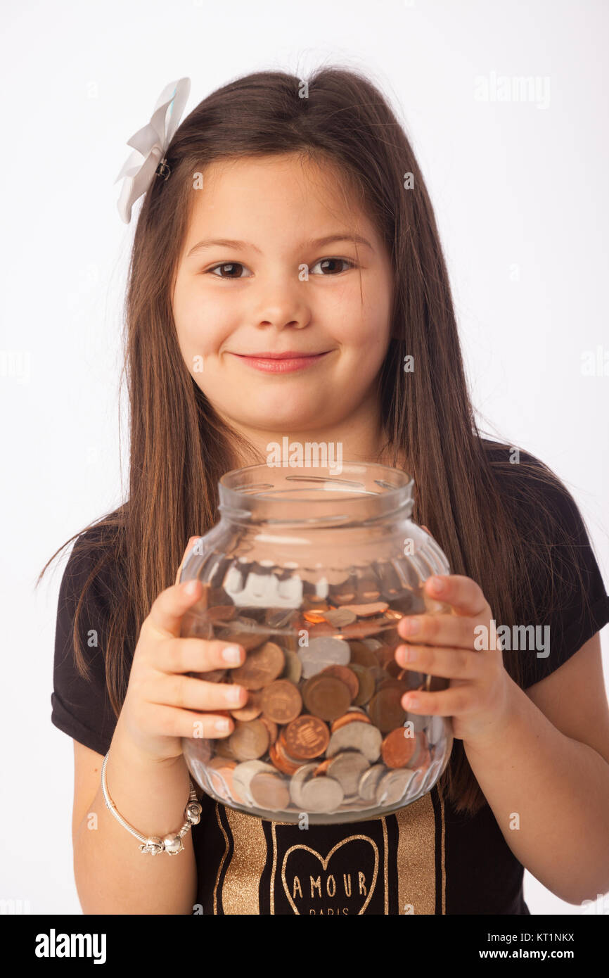 Seven year old girl holding a large jar full of coins Stock Photo