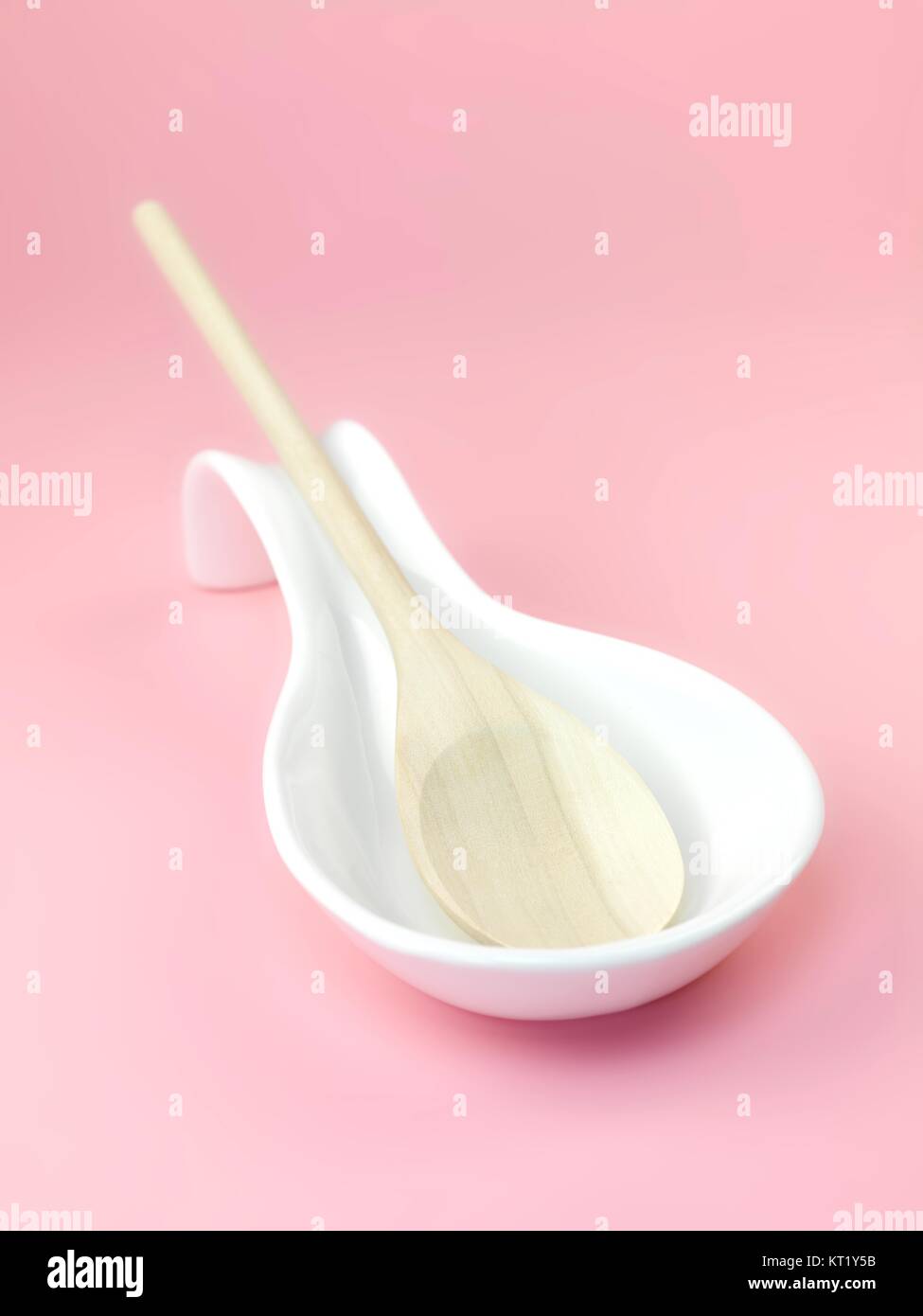 A wooden spoon in a resting laddle isolated against a pink background Stock Photo