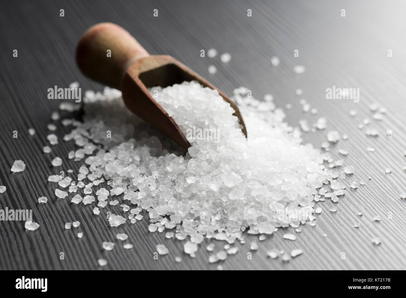 Sharp Salt Stuff wooden scoop with coarse salt on black table Stock Photo - Alamy