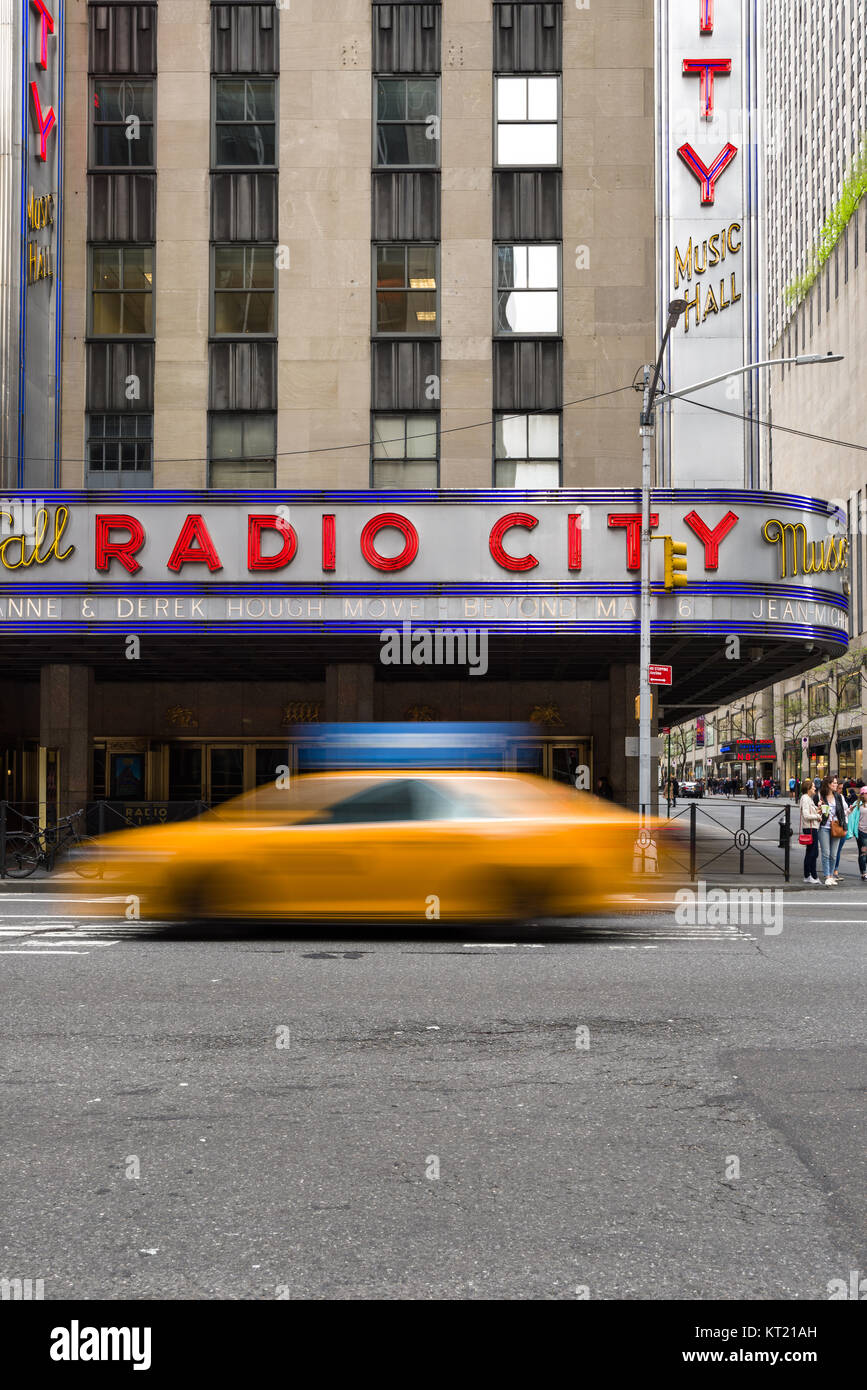 A yellow cab drives past the Radio City Music Hall building on 6th Avenue in Manhattan, New York, USA Stock Photo