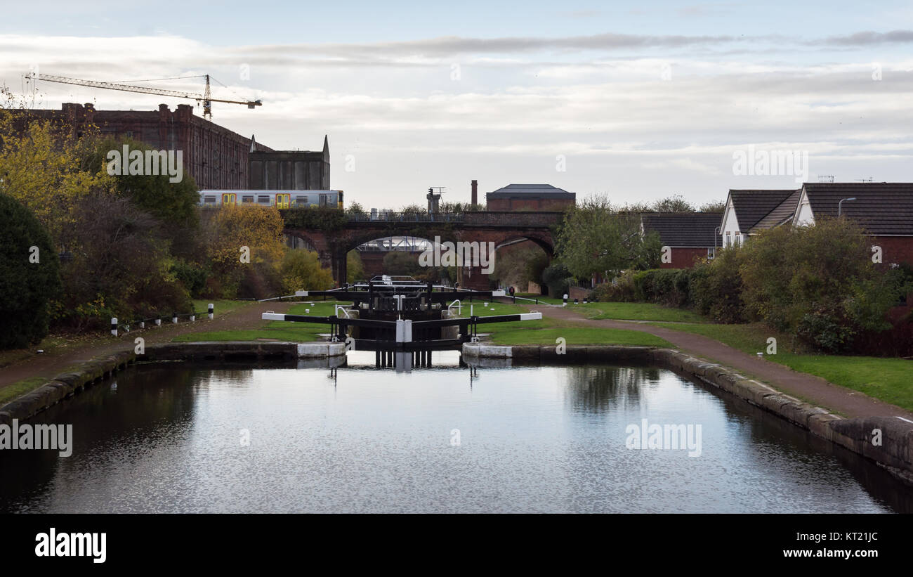 Liverpool, England, UK - November 12, 2016: A Merseyrail metro train crosses the Leeds & Liverpool canal at the Stanley Dock flight of locks in the Va Stock Photo