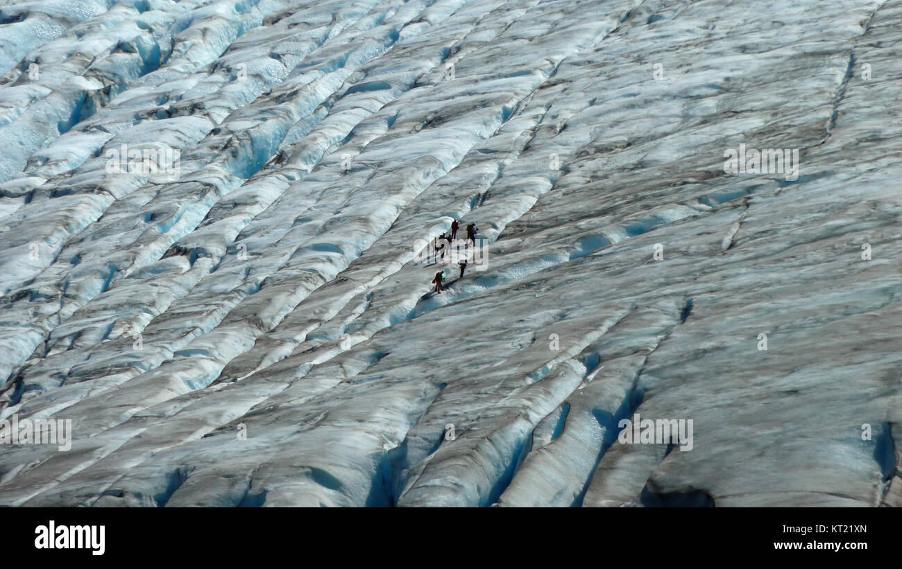 Small group of people walking on a glacier Stock Photo