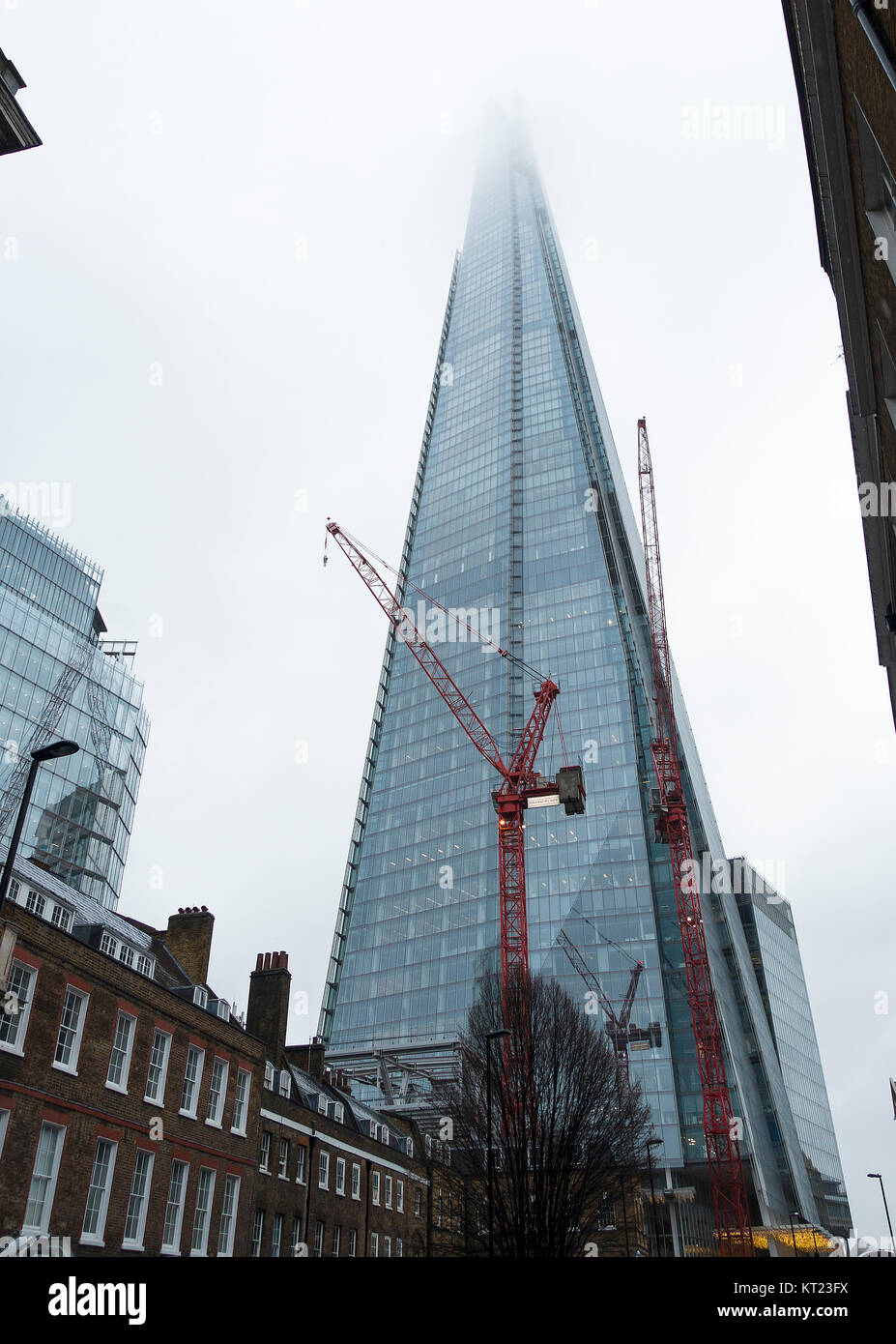 The Shard Skyscraper with its Top in Cloud and a Red Industrial Crane on a Cold Winter Day in December London England United Kingdom UK Stock Photo