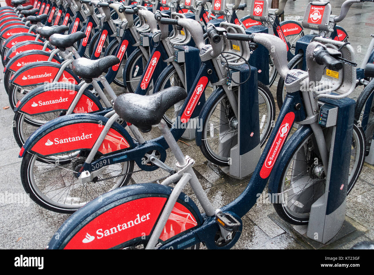 Lines of Red Rental Bicycles with Snow on Saddles Sponsored by Santander near Tower Bridge London England United Kingdom UK Stock Photo