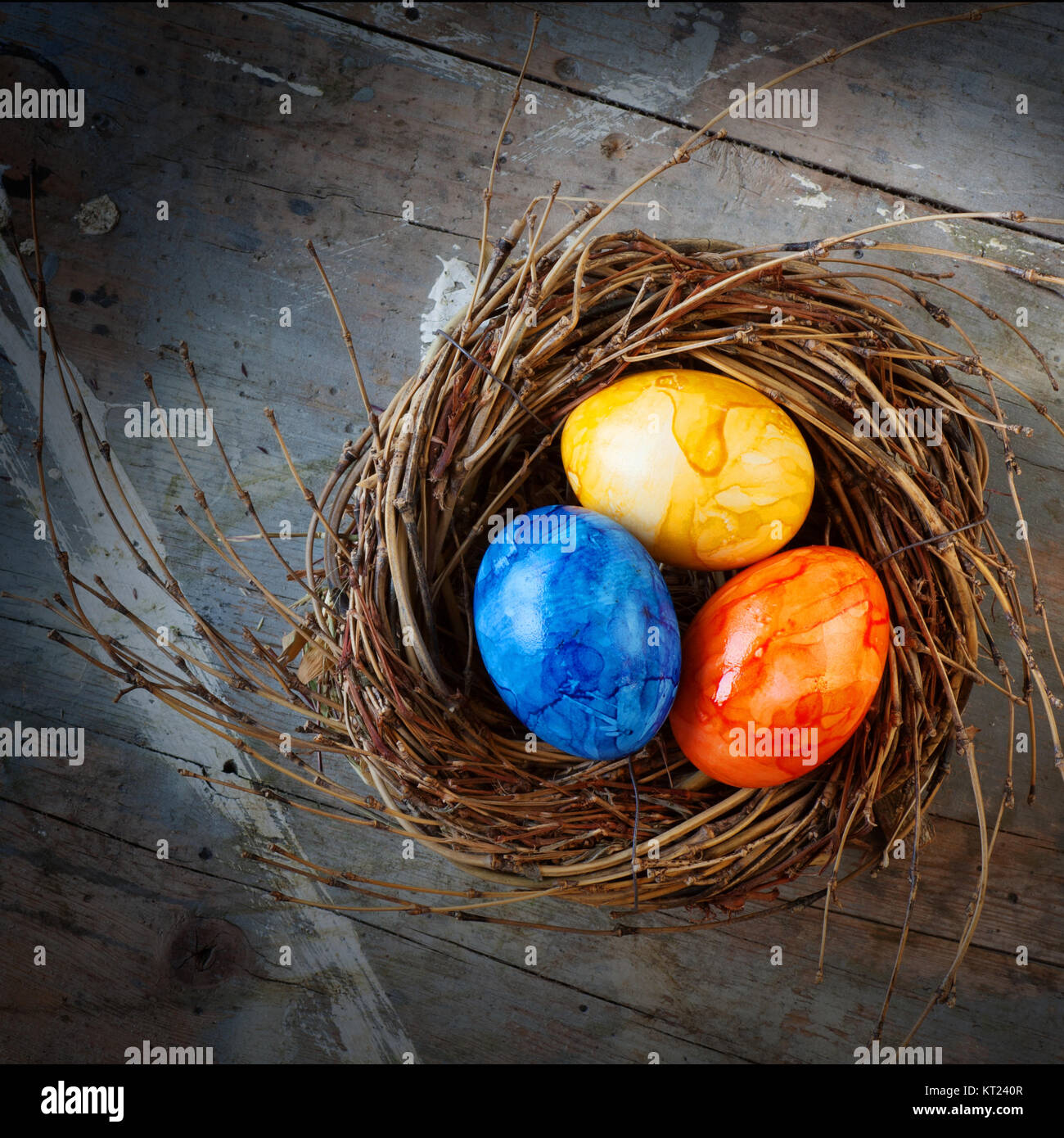 Colorful easter eggs in a nest from straw on a old shabby wooden table ...